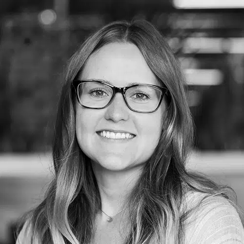 A woman's headshot with glasses smiling directly at the camera