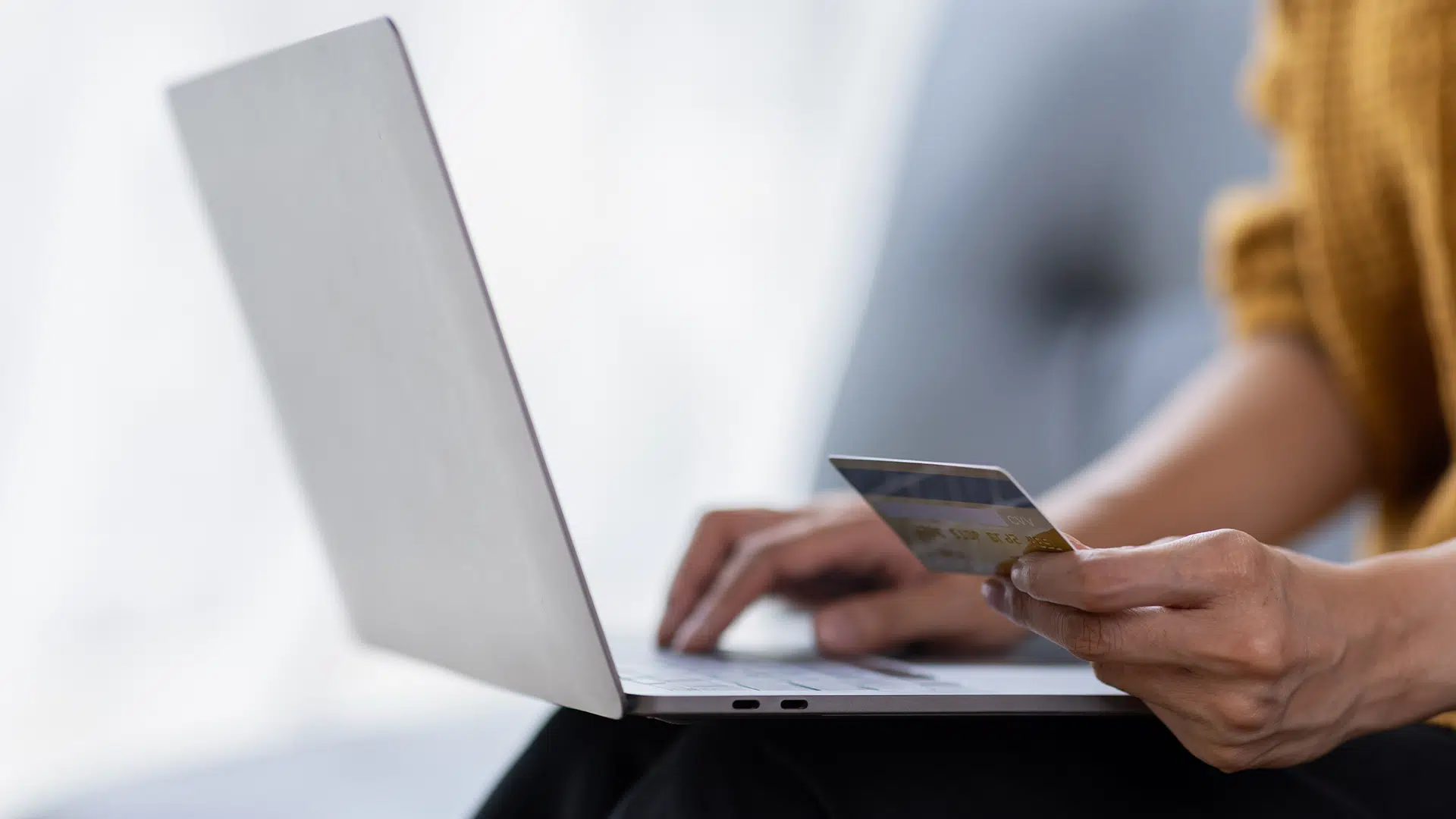 Person using a laptop and holding a credit card, illustrating secure first-party data collection for e-commerce retailers.