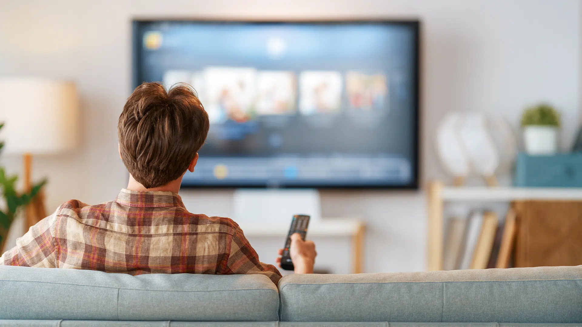 Man watching connected TV and navigating the menu with a remote.